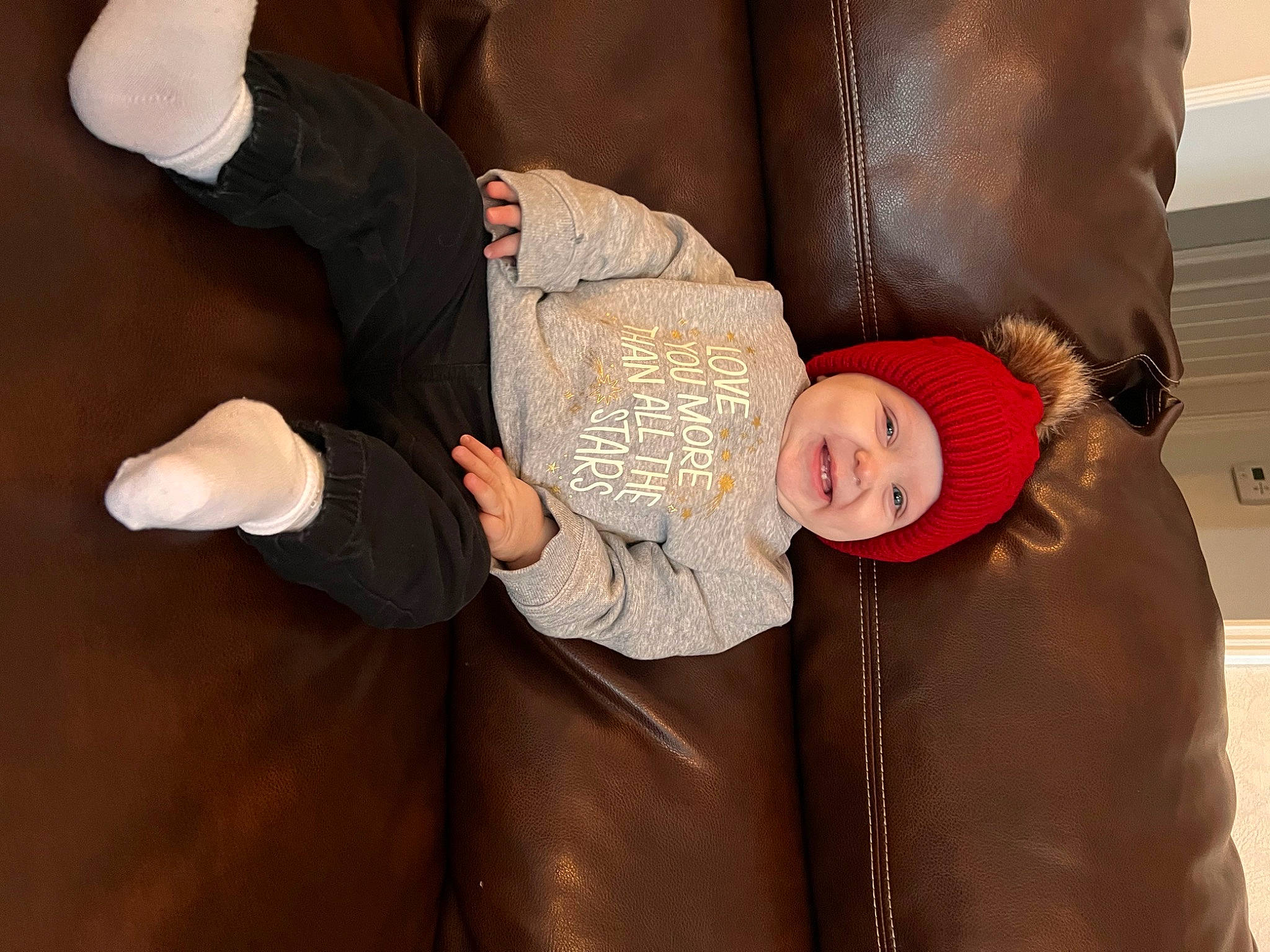 Hadley is registered to the contest to win money with this photo: baby, child, comfort, couch, event, formal_wear, fun, gesture, happy, head, headwear, lap, leather, outerwear, person, sitting, sleeve, smile, suit, thumb