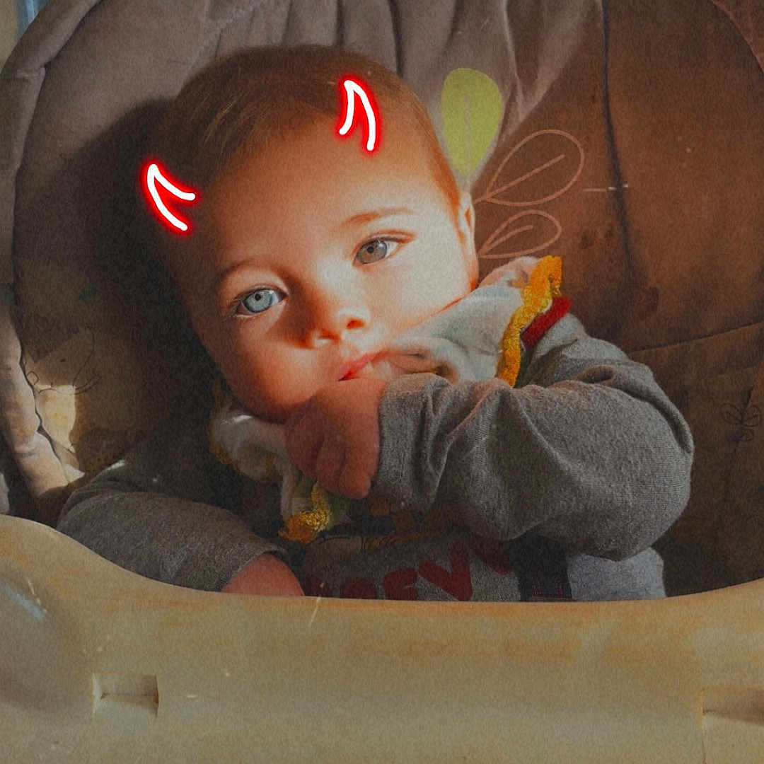 Kayde is registered to the contest to win money with this photo: baby, blue_eyes, casual, child, clothing, cute, devil_horns, digital_effect, expression, face, hand, high_chair, human, indoor, infant, person, playful, portrait, sitting, young_child