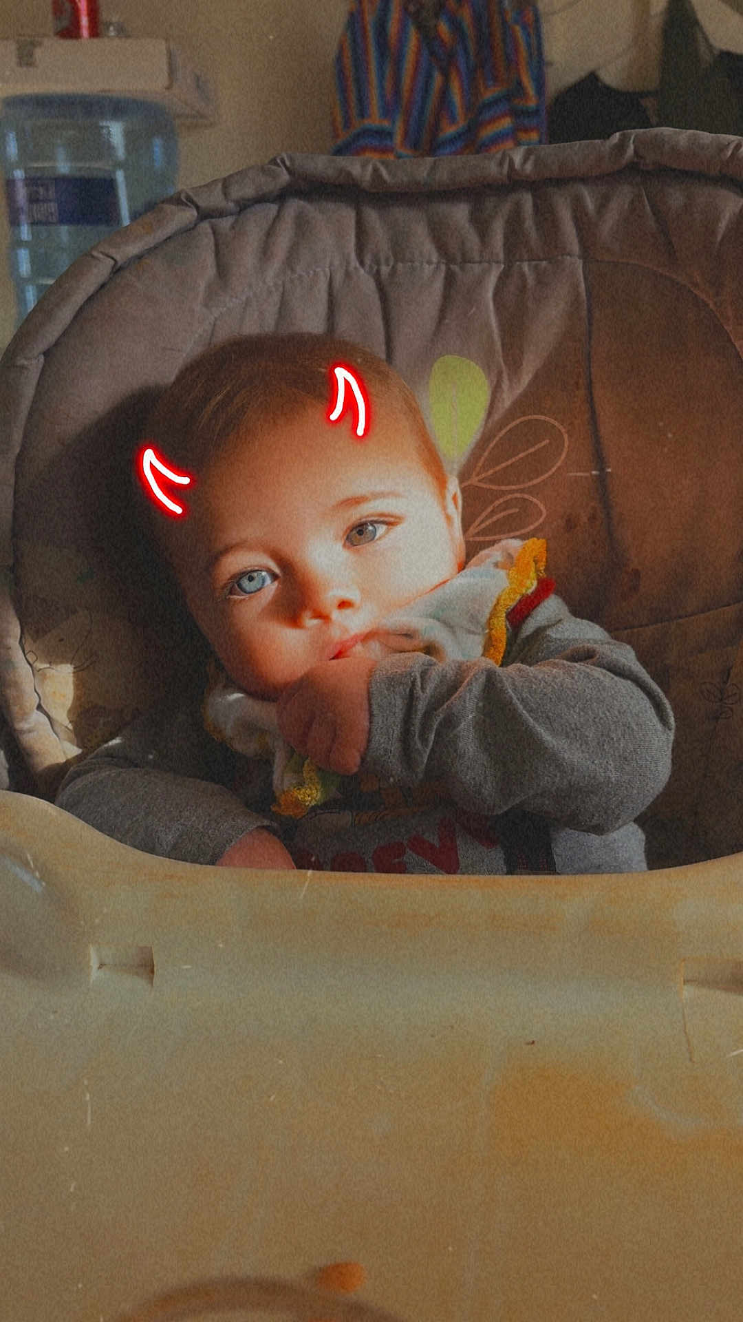 Kayde is registered to the contest to win money with this photo: baby, child, high_chair, blue_eyes, face, hand, clothing, indoor, sitting, cute, infant, digital_effect, devil_horns, playful, portrait, young_child, human, person, casual, expression