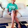 Camden joined the competition — help win amazing prizes! child, boy, smiling, sitting, couch, living_room, tshirt, barefoot, carpet, painting, home_interior, crossed_legs, happy, casual_clothing, shorts, furniture, indoor, person, portrait, relaxed