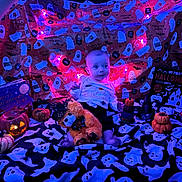 Mateo joined the competition — help win amazing prizes! baby, blanket, book, child, costume, cute, decorations, festive, ghost_pattern, halloween, holiday, indoors, jack_o_lantern, lights, orange, plush_toy, pumpkin, purple_lighting, seasonal, smiling