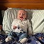 Mateo is registered to the contest to win money with this photo: baby, bed, blanket, blue, buttoned_shirt, child, clothing, cute, happy, indoor, infant, jeans, pacifier, person, pillow, portrait, sitting, smiling, socks, wooden_headboard