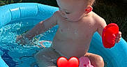 Mateo is registered to the contest to win money with this photo: toddler, child, pool, water, splashing, toy, inflatable_pool, blue, sunlight, outdoor, summer, barefoot, hand, playing, motorcycle, grass, garden, happy, skin, cute