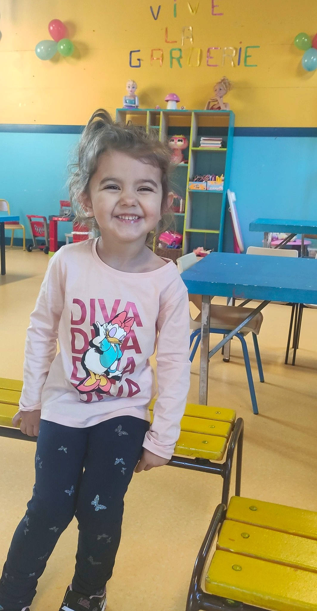 Emmy participe au concours pour gagner de l'argent avec cette photo : chair, child, clothing, fun, hairstyle, happy, joy, kindergarten, leg, leisure, person, play, recreation, room, sleeve, smile, sportswear, standing, t_shirt, table