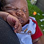 baby, black, closeup, clothing, cute, face, grass, hand, infant, newborn, outdoor, peaceful, person, portrait, red, resting, skin, sleeping, toddler, white