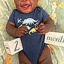 baby, blanket, celebration, child, close_up, colorful, cute, dinosaur_onesie, giraffe_pattern, hands, happy, indoors, infant, legs, lying_down, months_sign, portrait, smiling, tongue_out, wooden_block