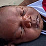 Robert is registered to the contest to win money with this photo: baby, child, closeup, clothing, curly_hair, dark_skin, face, hand, head, indoors, peaceful, portrait, red, relaxation, resting, sleeping, soft_skin, toddler, white, young_child