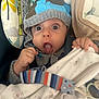 baby, child, face, hat, knitwear, blanket, hand, tongue, expression, wide_eyes, pacifier, clothing, infant, comfort, soft, striped, blue, gray, white, cute
