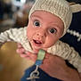 baby, infant, knit_hat, hand, pacifier, close_up, cute, wide_eyes, portrait, soft_focus, indoors, expression, child, wearing, person, holding, warm_clothing, adorable, young, headwear