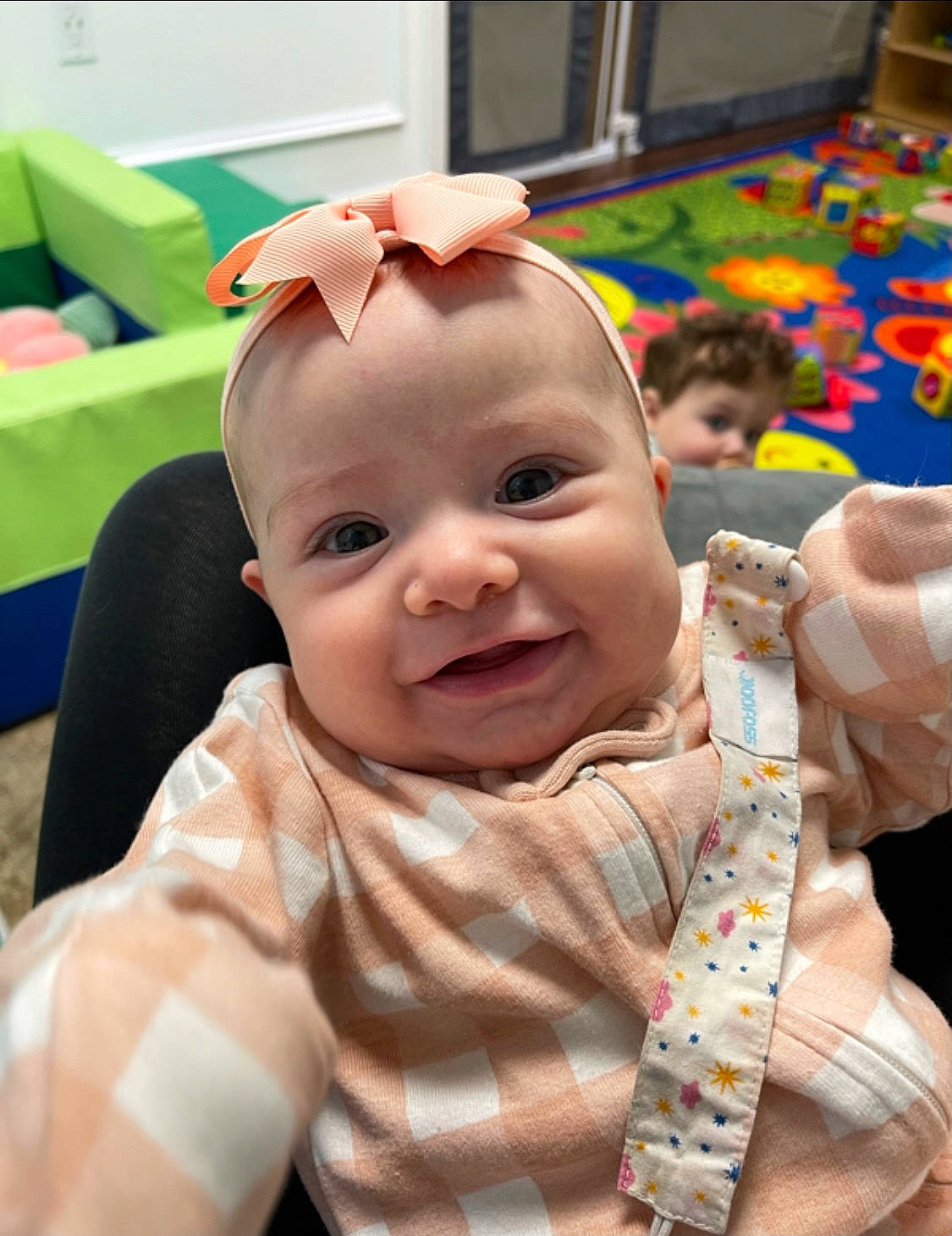 Sofia is registered to the contest to win money with this photo: baby, baby_products, baby_toddler_clothing, cheek, child, chin, event, face, fun, gesture, grass, green, happy, joy, leisure, person, room, sitting, skin, smile