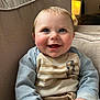 baby, child, smiling, blue_eyes, couch, striped_shirt, long_sleeves, beige, indoor, lamp, happy, cute, hands, clothing, portrait, young_child, sitting, cozy, home, bright