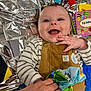 baby, child, smiling, overalls, striped_shirt, toy, hand, tattoo, blue_eyes, playtime, colorful, fabric, happy, infant, cute, indoor, soft_toy, background, closeup, portrait