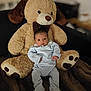 adorable, baby, blanket, blue_onesie, child, comfort, cozy, cuddly, cute, indoors, infant, plush, portrait, sitting, sleepwear, smiling, soft_toy, teddy_bear, toy, young