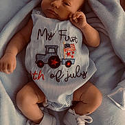 Jasper is registered to the contest to win money with this photo: baby, infant, blanket, clothing, shoes, blue, striped, text, floor, wood, cute, young_child, portrait, laying_down, small_shoes, soft_texture, comfortable, indoors, celebration, holiday_outfit