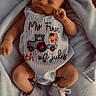 baby, infant, blanket, clothing, shoes, blue, striped, text, floor, wood, cute, young_child, portrait, laying_down, small_shoes, soft_texture, comfortable, indoors, celebration, holiday_outfit