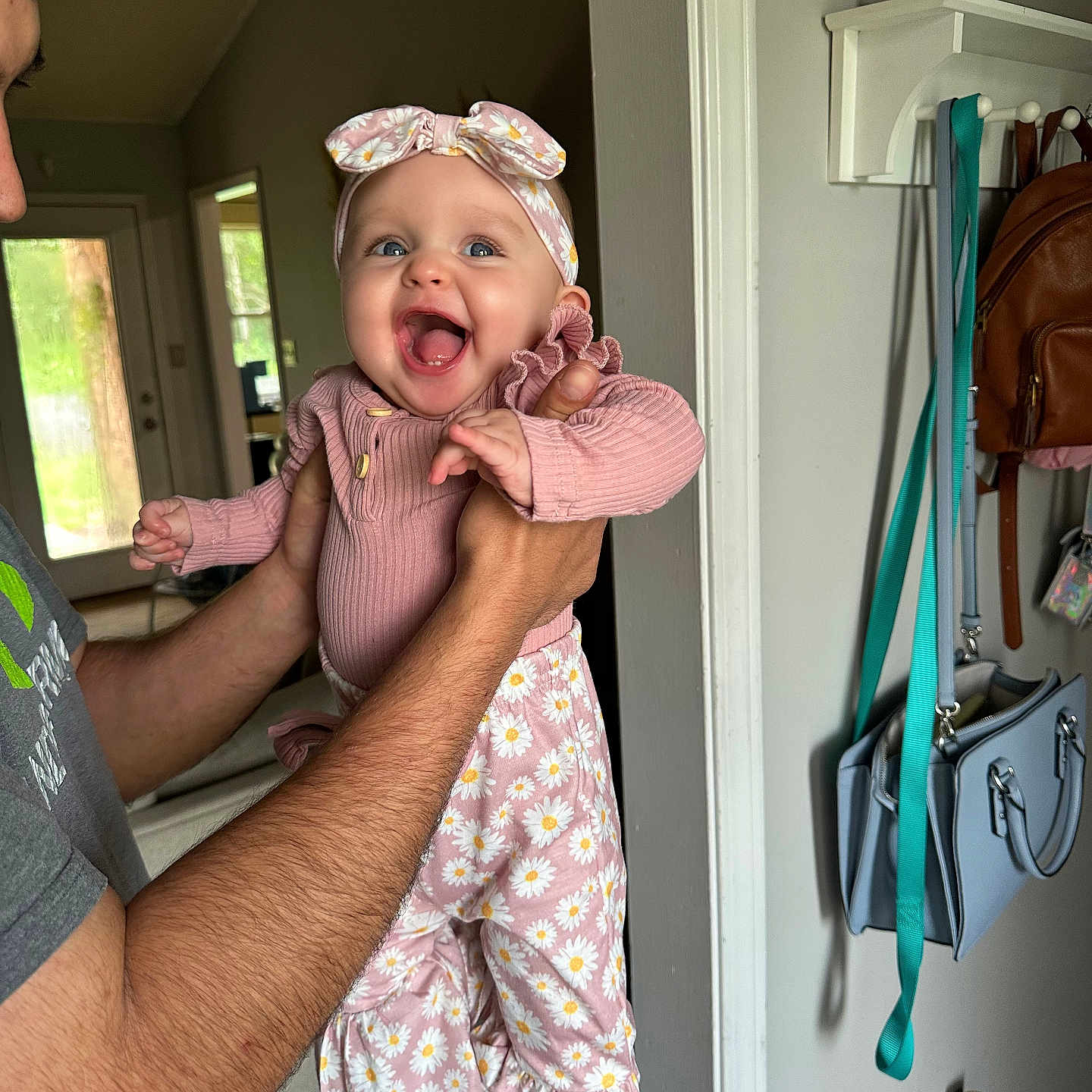Hannah Claire joined the competition — help win amazing prizes! adult_hand, baby, bag, child, cute, daisies, door, face, happy, headband, holding, home, hook, indoor, patterned_pants, person, pink_clothing, portrait, smiling, striped_socks