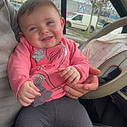 Amélia a rejoint le concours — aidez-le/la à gagner de superbes lots ! baby, car_interior, casual, child, cute, gray_leggings, hand, happy, human, indoor, person_holding_child, pink_clothing, portrait, seat, sitting, smiling, steering_wheel, vehicle, window, young_child