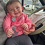 baby, car_interior, casual, child, cute, gray_leggings, hand, happy, human, indoor, person_holding_child, pink_clothing, portrait, seat, sitting, smiling, steering_wheel, vehicle, window, young_child