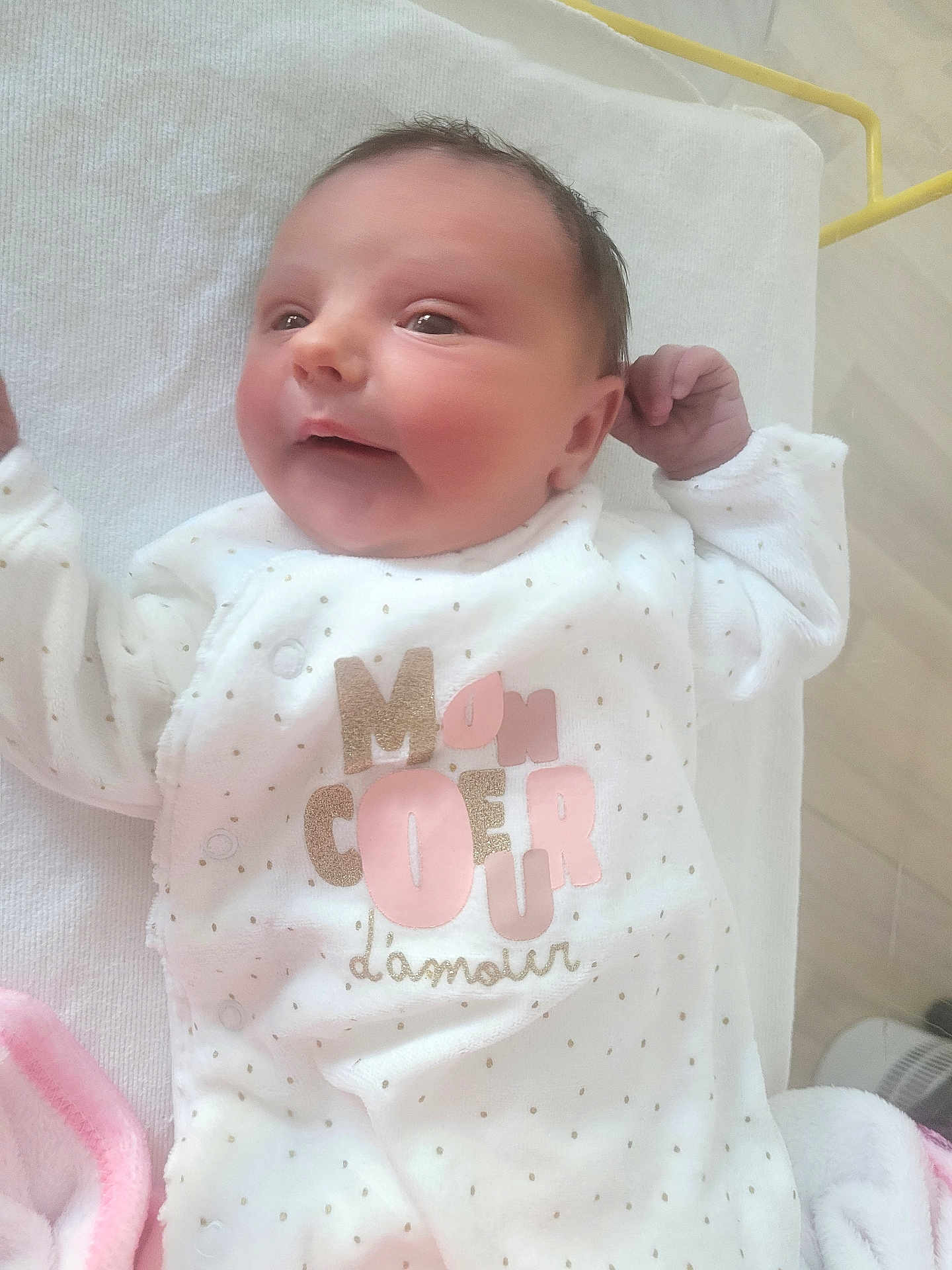 Zoé a rejoint le concours — aidez-le/la à gagner de superbes lots ! baby, infant, newborn, white_clothing, blanket, smiling, face, cute, sleepwear, lying_down, soft_texture, pink, gold, dots, hand, head, eyes, skin, portrait, indoors