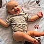 baby, smiling, infant, blanket, cute, happy, lying_down, child, soft_texture, patterned_clothing, heart, rainbow, playful, arm_band, skin, foot, head, face, expression, indoors