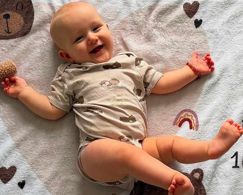 Leandro a rejoint le concours — aidez-le/la à gagner de superbes lots ! baby, smiling, infant, blanket, cute, happy, lying_down, child, soft_texture, patterned_clothing, heart, rainbow, playful, arm_band, skin, foot, head, face, expression, indoors