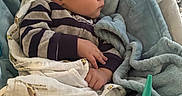 Kaziel is registered to the contest to win money with this photo: baby, infant, child, portrait, sitting, bouncer, blanket, swaddle, striped_clothing, brown_hair, face, profile, serious_expression, indoor, nursery, soft_blanket, cushion, carpet, baby_accessory, green_object