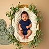 Kaziel joined the competition — help win amazing prizes! baby, infant, child, portrait, lying_down, basket, blanket, knitted_blanket, greenery, leaves, plants, sage_cloth, navy_clothing, cozy, studio_photo, warm_lighting, centered_composition, indoor, sleepy, newborn_photography