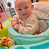 baby, child, infant, smiling, portrait, sitting, activity_center, baby_toys, playroom, indoor, face, eyes, hands, clothing, cushion, plastic_toy, colorful, happy, home, photography