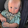 baby, infant, child, portrait, car_seat, seated, wide_eyes, blue_eyes, serious_expression, fair_skin, mint_green_shirt, graphic_shirt, blanket, hands, arms, indoor, close_up, photography, safe, vehicle