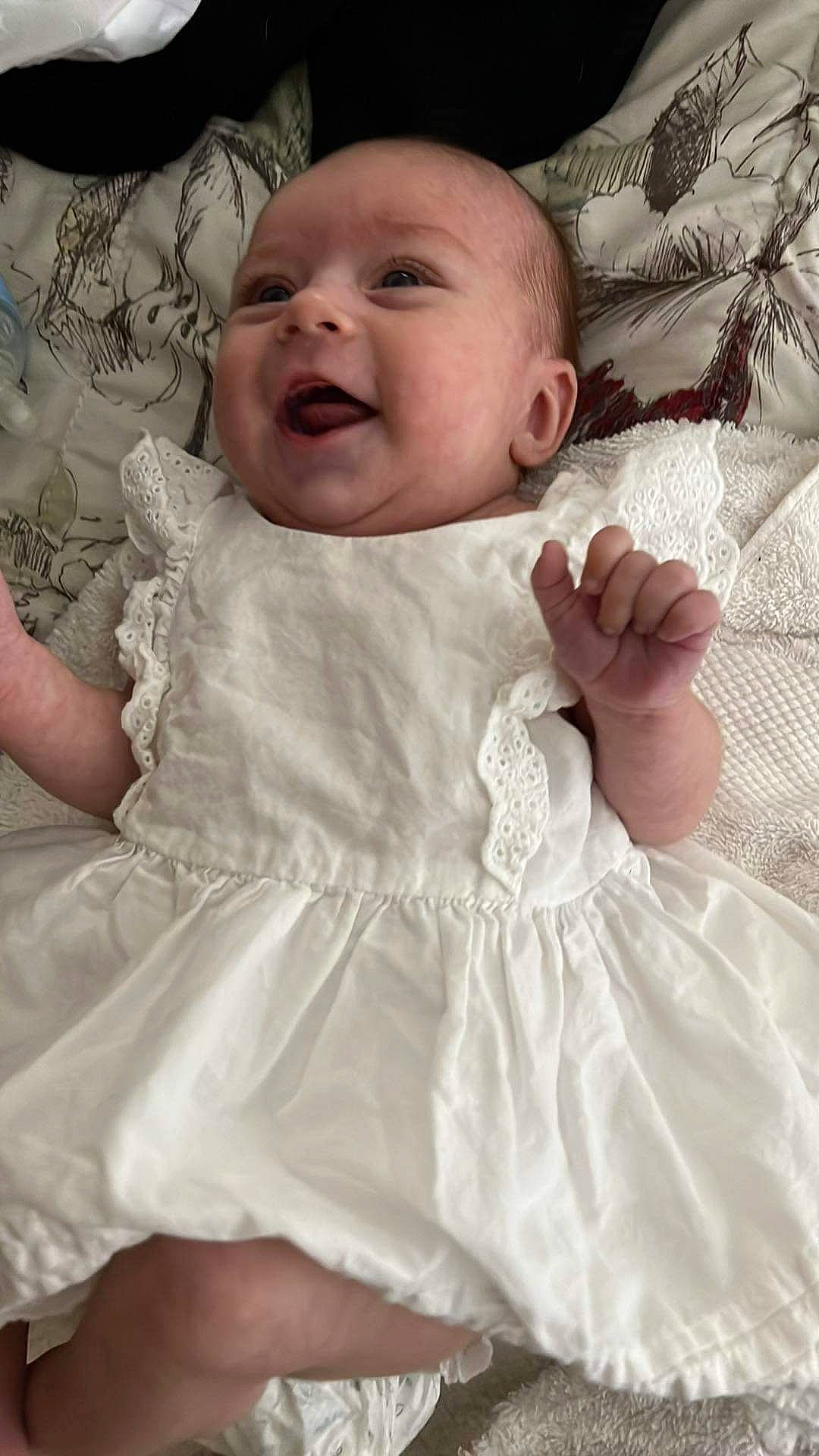 Riley is registered to the contest to win money with this photo: baby, baby_toddler_clothing, cheek, chin, comfort, dress, eye, face, facial_expression, gesture, hand, happy, head, iris, lip, person, pink, skin, sleeve, smile