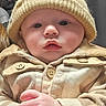 Noah is registered to the contest to win money with this photo: baby, infant, child, portrait, close_up, face, eyes, hat, knitwear, clothing, outfit, buttons, hands, indoors, cozy, calm, serious_expression, sitting, photography, human