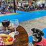 blue_floor, chihuahua, crowd, dog, event, exhibition, food, hot_dog, indoor, leash, leather_jacket, motorbike, motorcycle, people, pet, plastic_glass, seat, table, wine, wooden_table
