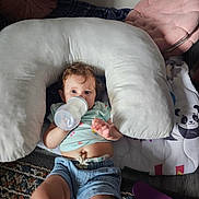 Charlotte joined the competition — help win amazing prizes! baby, bottle, drinking, pillow, denim_shorts, blue_shirt, panda_blanket, pink_cushion, carpet, floor, indoor, child, cute, soft_toys, relaxing, lying_down, nursing_pillow, infant, casual_clothing, home