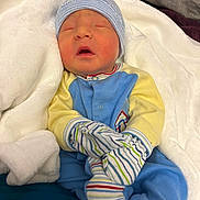 Hylan joined the competition — help win amazing prizes! newborn, baby, infant, sleeping, blanket, mittens, hat, clothing, blue, yellow, striped, cozy, soft, bed, rest, cute, portrait, child, person, indoors