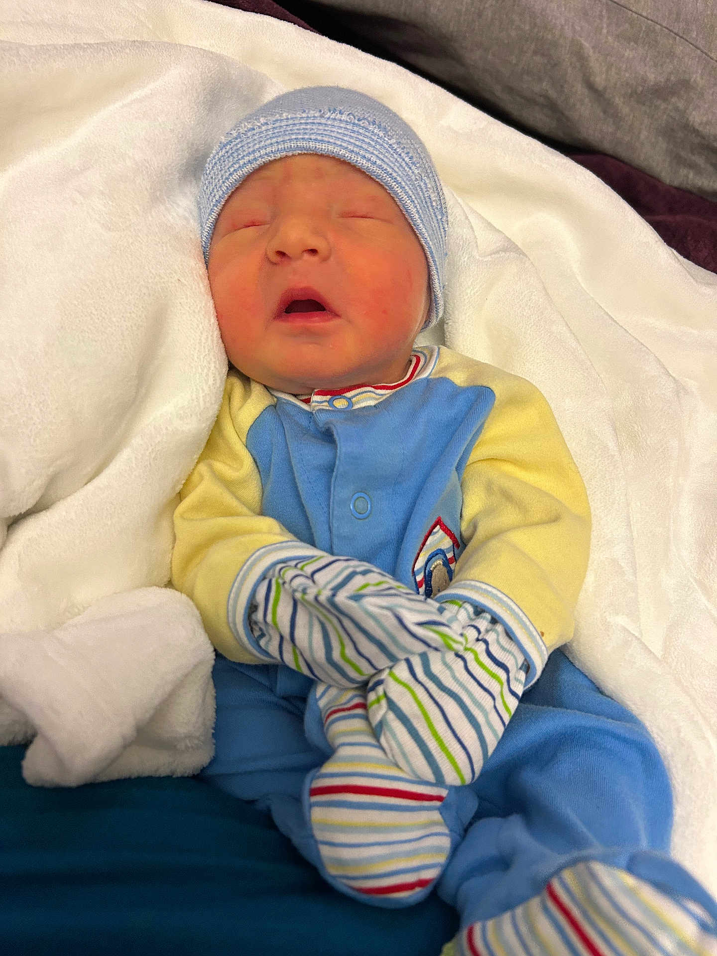 Hylan joined the competition — help win amazing prizes! newborn, baby, infant, sleeping, blanket, mittens, hat, clothing, blue, yellow, striped, cozy, soft, bed, rest, cute, portrait, child, person, indoors