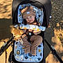 Jaxson is registered to the contest to win money with this photo: animal_print, baby, child, clothing, face, happy, hat, infant, outdoor, pattern, plush_toy, safety_harness, seated, shadow, sidewalk, smile, stroller, sunlight, toy, transport