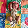 baby, cartoon_animals, child, colorful, crocodile, cute, elephant, fun, giraffe, happy, indoors, infant, lying_down, onesie, owl, person, play_mat, playful, smiling, socks
