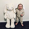 Jaxson joined the competition — help win amazing prizes! toddler, child, plush_toy, bunny, onesie, hoodie, indoor, carpet, wall, smiling, barefoot, cute, toy, childhood, playful, friendship, soft_toy, baby, standing, happy