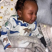 Tyriq joined the competition — help win amazing prizes! baby, sleeping, blanket, onesie, dinosaur, cute, cozy, infant, child, smile, bed, soft, fabric, pattern, animal_print, comfort, rest, peaceful, indoors, portrait