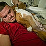 animal, bed, blanket, canine, casual, comfort, dog, face, friendship, furniture, home, human, indoor, man, nap, pet, red_shirt, relaxation, resting, sleeping
