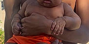 Khamari is registered to the contest to win money with this photo: adult, arms, baby, child, curly_hair, cute, daytime, expression, holding, infant, legs, orange_shorts, outdoor, person, portrait, skin, summer, sunlight, warm, young