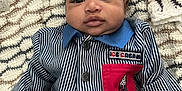 Khamari is registered to the contest to win money with this photo: baby, child, curly_hair, striped_jacket, red_pocket, ice_cream_patch, blanket, knitted_blanket, cozy, portrait, infant, cute, face, clothing, buttoned_jacket, lying_down, indoors, young_child, expression, person