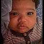 baby, infant, face, hands, striped_clothing, button, blanket, stars_pattern, curly_hair, close_up, lying_down, cute, child, person, indoors, soft_lighting, skin, expression, comfort, toddler