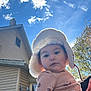 autumn, baby, blanket, building, child, clouds, coat, curious, daylight, face, hat, house, nature, outdoor, person, portrait, sky, smiling, tree, warm_clothing