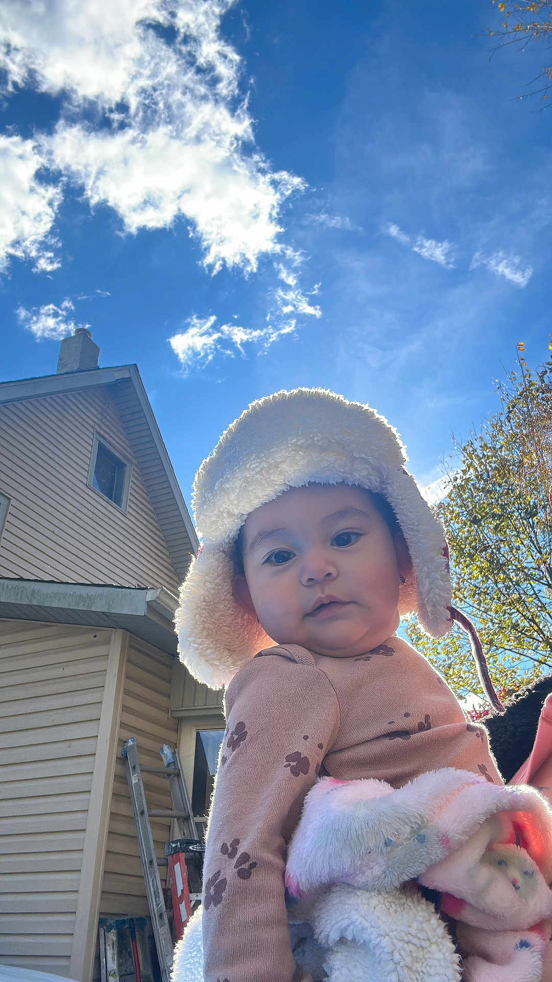 Brianna is registered to the contest to win money with this photo: autumn, baby, blanket, building, child, clouds, coat, curious, daylight, face, hat, house, nature, outdoor, person, portrait, sky, smiling, tree, warm_clothing