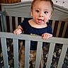 Anthony joined the competition — help win amazing prizes! baby, crib, child, infant, blue_shirt, beige_pants, wooden_wall, calendar, handwriting, standing, gripping, railing, playful_expression, tongue_out, indoor, furniture, person, smiling, cute, young_child