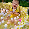toddler, child, smiling, yellow_shirt, plastic_balls, ball_pool, yellow_checkered_cloth, outdoor, grass, garden, summer, happy, play, water, small_pool, person, toy, fun, sitting, daytime