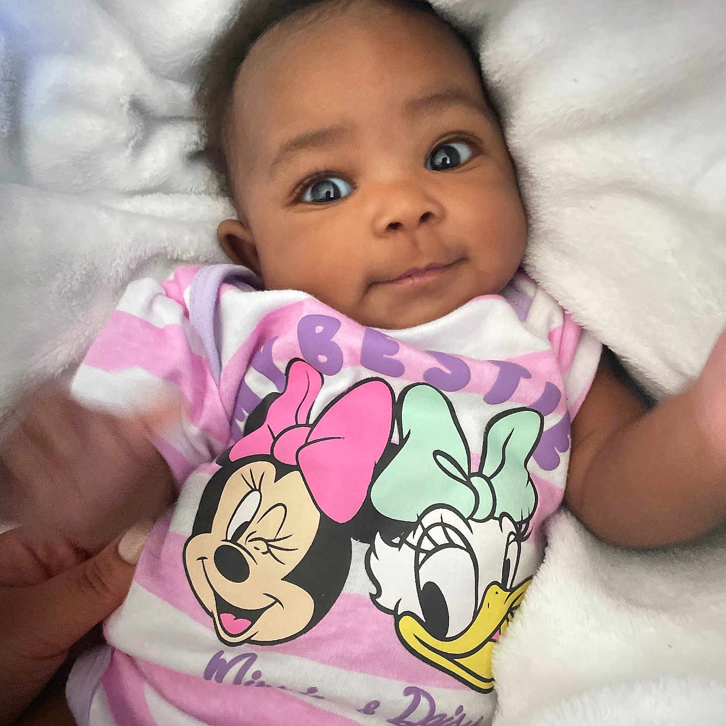 Carli is registered to the contest to win money with this photo: baby, infant, child, portrait, face, smiling, wide_eyed, lying_down, blanket, fluffy, white_blanket, pink_clothing, baby_outfit, minnie_mouse, cartoon, disney, indoor, close_up, adorable, photography