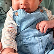 Zayn joined the competition — help win amazing prizes! baby, child, face, denim_overalls, striped_shirt, hand, smile, eyes, hair, skin, couch, pillow, indoor, portrait, infant, cute, happy, clothing, person, closeup