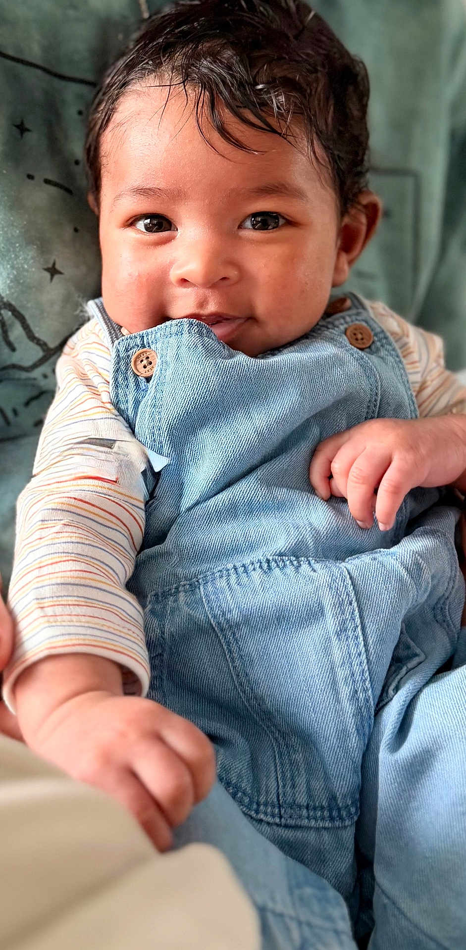 Zayn joined the competition — help win amazing prizes! baby, child, face, denim_overalls, striped_shirt, hand, smile, eyes, hair, skin, couch, pillow, indoor, portrait, infant, cute, happy, clothing, person, closeup